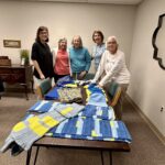 women displaying their knitted and crocheted items